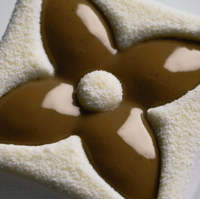 A close-up of a star-shaped ice cream treat with a central ball and four petal-shaped segments covered in a light, fluffy coating.