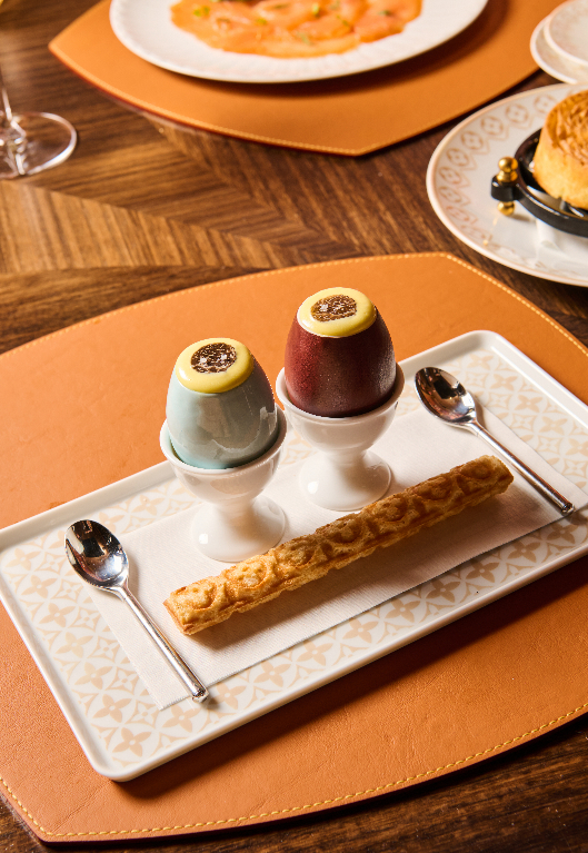 Succulent chicken dish with vibrant orange sauce being drizzled over it, garnished with fresh herbs.